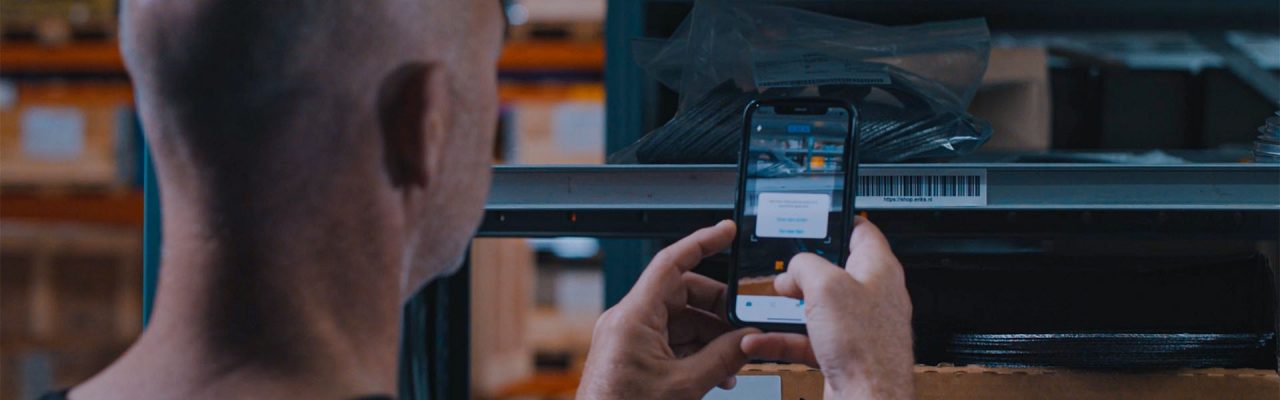 A person scanning a barcode with his mobile phone, using the ERIKS App in a warehouse