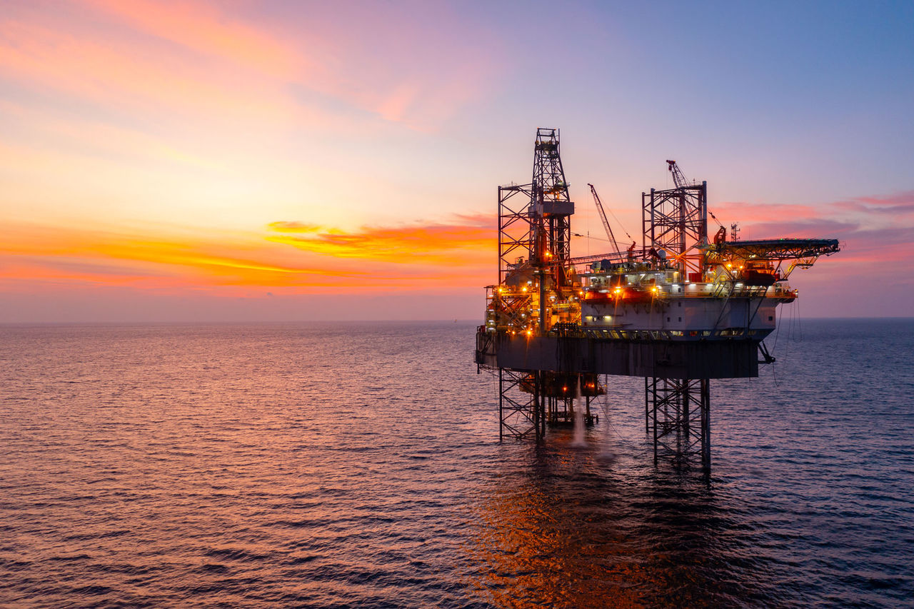 Oil and Gas Industry sunset photo - Aerial view of silhouette offshore jack up drilling rig during sunset - oil and gas industry