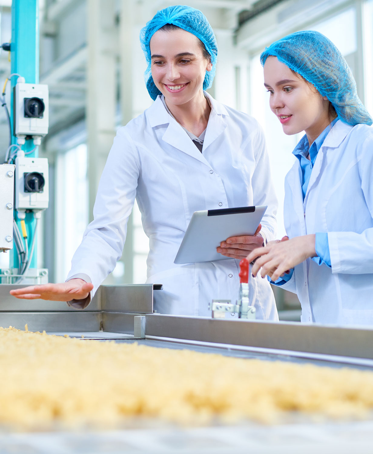 two women in hairnets with clipboard checking food production 