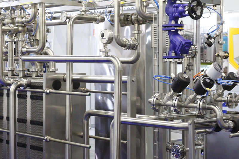 Stainless steel pipes in a food factory. Stainless pipe fittings. Tubular heat exchangers. Food pumps. A fragment of a dairy plant. 