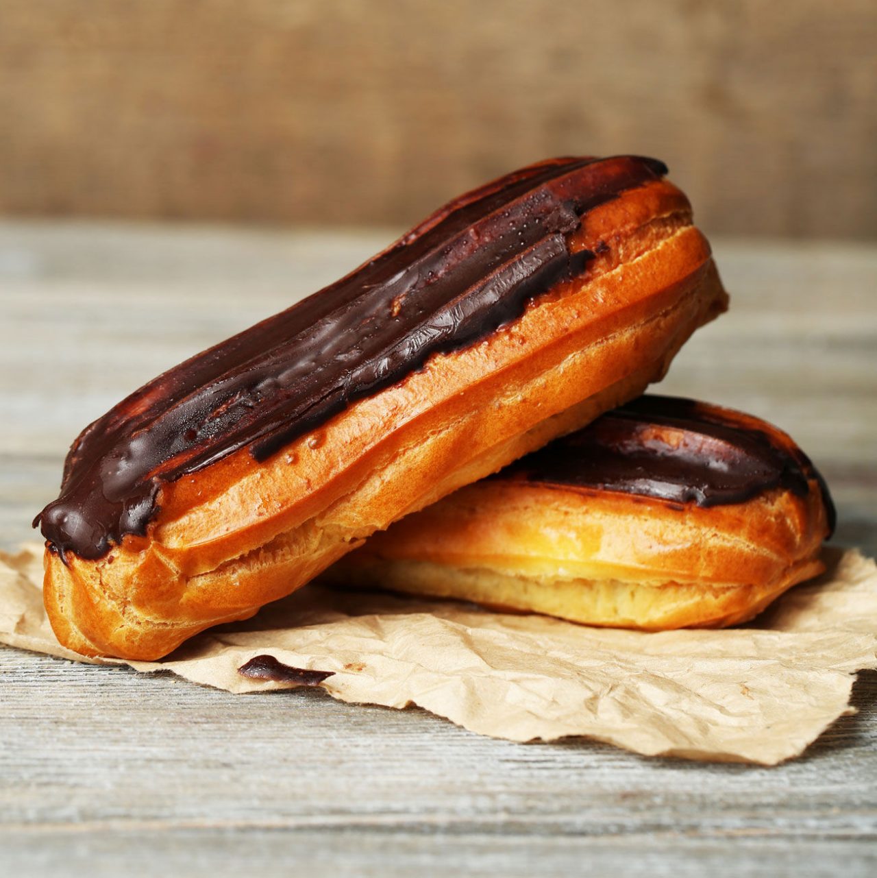 Tasty eclairs on wooden table, close up