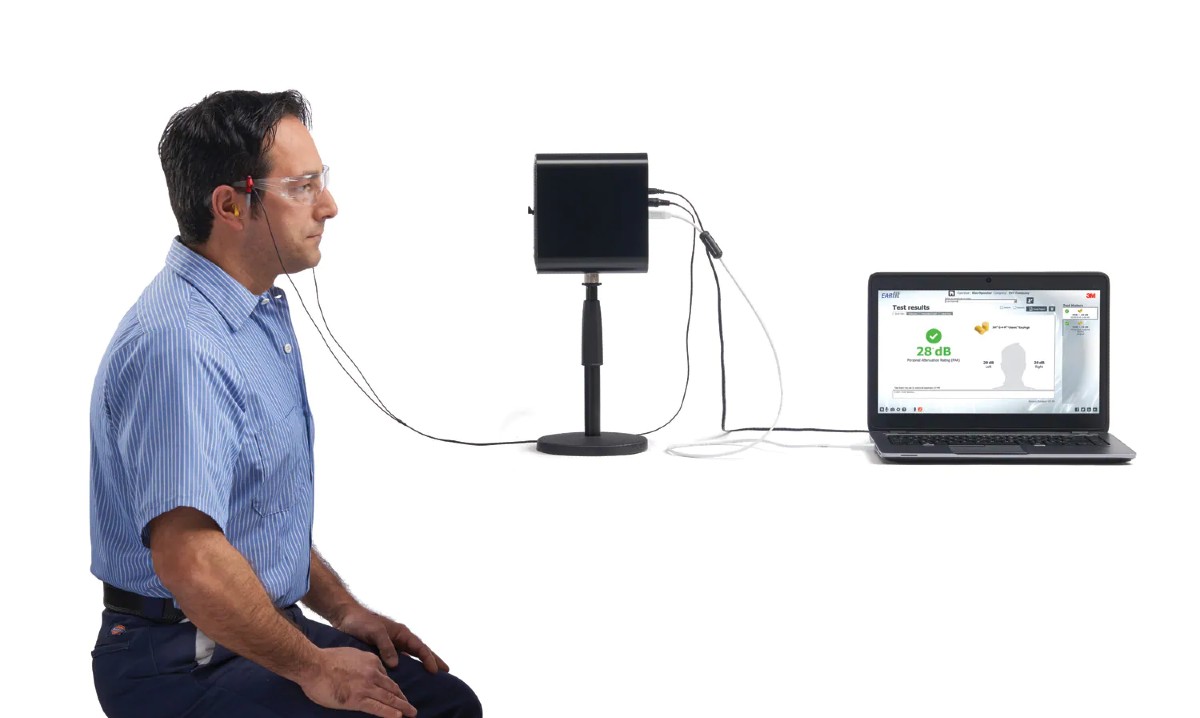 Protective hearing test equipment with a man, testing machinery and laptop