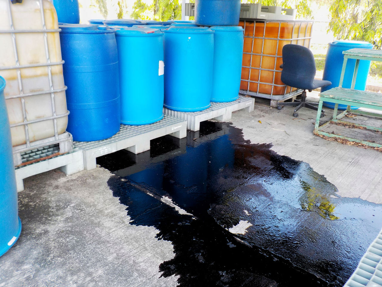 Black liquid chemicals leaking from the tank into the floor.