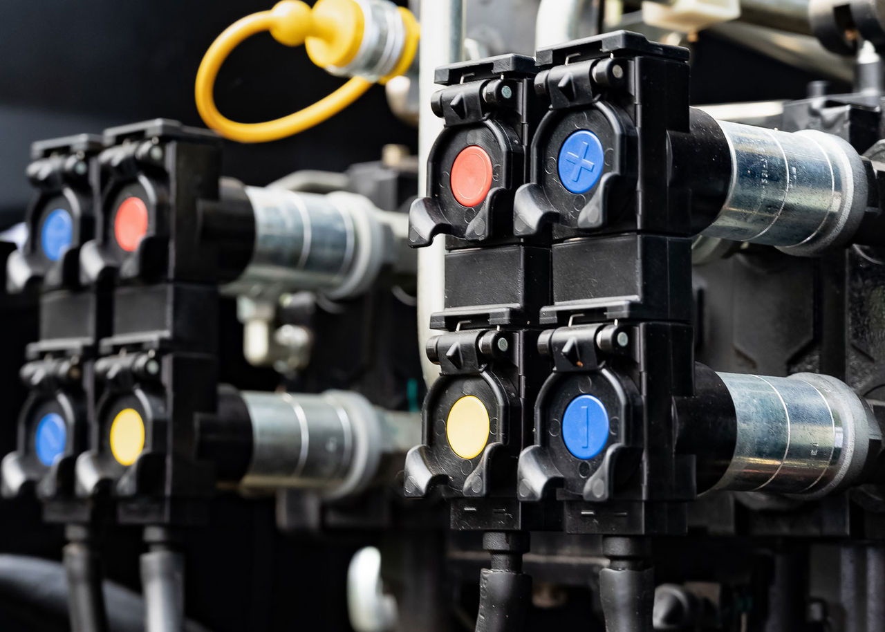 Close-up of hydraulic connectors and valves on industrial equipment. Hydraulic hose connectors